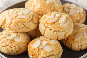 Crispy shortbread cookies with almond flakes close-up in a plate on a wooden table. Horizontal