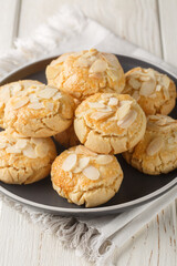 Cracked almond cookies vegetarian and gluten-free close-up in a plate on a wooden table. Vertical