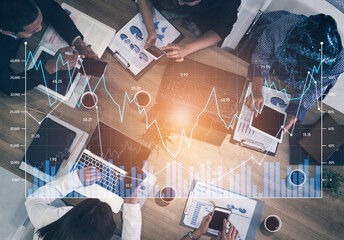 A dynamic team working together over laptops and documents, analyzing business data and trends with...