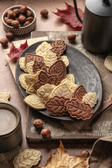 Autumn leaf shaped shortbread cookies with coffee cup on brown rustic table