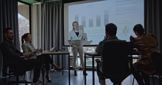 Young business associates analyze graphs and statistics during a team meeting. They discuss their strategy and project plans. - Powered by Adobe