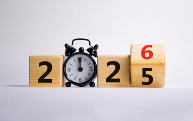 2026 New Year symbol. Businessman turns wooden cube and changes Year 2025 to 2026. Beautiful white background with Alarm clock. Copy space. Business and 2026 happy new year concept