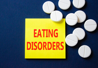 Eating Disorders symbol. Concept word Eating Disorders on yellow note. Beautiful deep blue background with pills. Medicine and Eating Disorders concept. Copy space