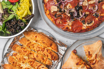 Salad, pepperoni pizza, cheesy breadsticks, and a folded calzone.