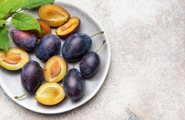Fresh plums on plate showing halved fruit composition
