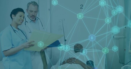 Reviewing medical chart doctor and scrub-clad nurse beside hospital bed, displaying network overlay