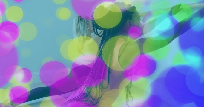 Fototapeta Reaching partners in athletic wear holding ballet barre at dance studio, with translucent circles