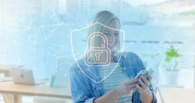 Smiling office professional holding smartphone in modern workspace, showing digital shield concept