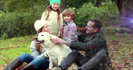 Fototapeta premium Sitting family of four holding and petting white dog at wooded park clearing, fallen leaves