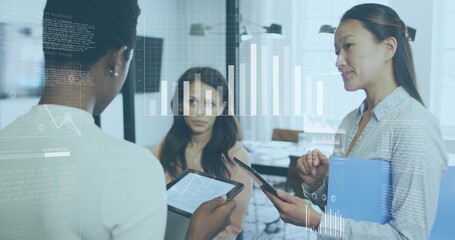 Collaborating businesswomen analyzing data in office meeting room, with tablets and hologram charts