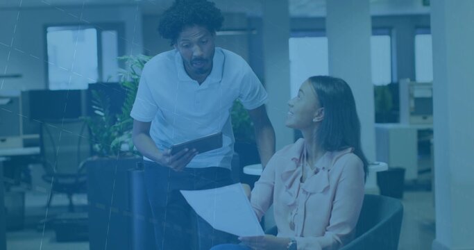 Discussing mid adult colleagues collaborating in casual office lounge, with tablet and document - Powered by Adobe