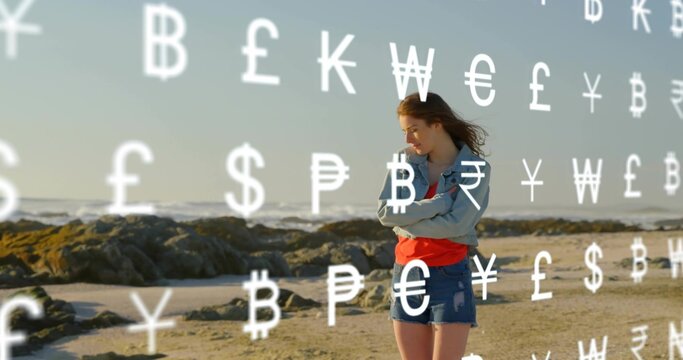 Standing woman wearing denim jacket and shorts crossing arms on beach, currency symbols, copy spac