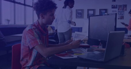 Analyzing Asian coworker reviewing printed papers beside laptop in coworking space, copy space