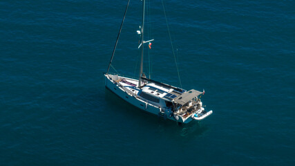 Aerial view of a sailboat anchored in the middle of the blue sea. Boat holiday concept. Isolated vessel.