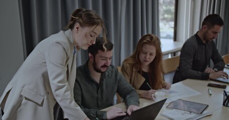 University students collaborate on a project, using a laptop and taking notes. Teamwork and focus are evident in this modern workspace. - Powered by Adobe