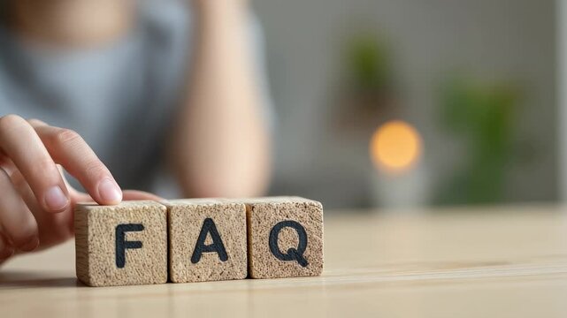 Close up view of a person's hand arranging wooden blocks to spell out faq, representing the concept of frequently asked questions, customer support, and providing essential information - Powered by Adobe