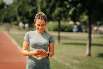 Sporty woman using smartphone on running track after workout