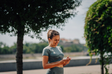 Sportswoman using smartphone app in city park: tracking fitness progress