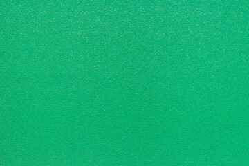 A detailed, full-frame texture of the synthetic green surface of a badminton court, providing an excellent abstract background showcasing the material's granular structure.