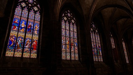 Fototapeta premium Gothic stained glass windows casting colored light in medieval cathedral, highlighting columns