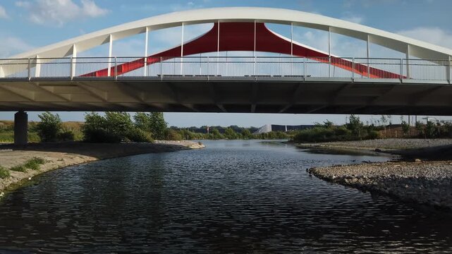 View of Don River flowing under the Commissioners Street bridge in the newly formed Biidaasige Park in Toronto's Port Lands, wide shot