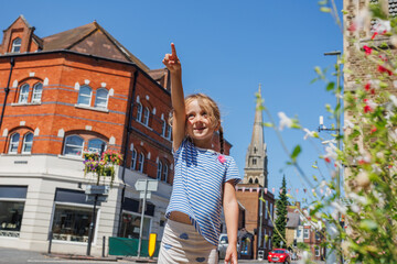 Happy child in striped shirt points at sunny town Farnham, UK