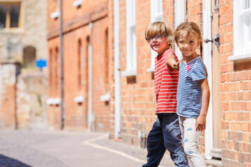 Two kids happily walking along sunny historic street in Farnham