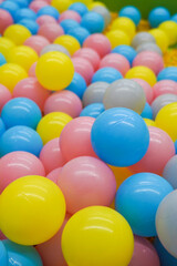A pile of colorful plastic balls in various hues like blue, pink, yellow, and gray
