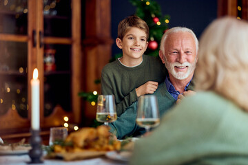 Fototapeta premium Joyful Grandfather And Grandson Share Festive New Year Dinner With Family