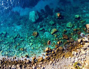 Aerial view of clear turquoise sea meeting a rocky shoreline