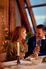 Romantic Couple Enjoys Cozy Christmas Eve Dinner By Candlelight With Wine And Holiday Decor