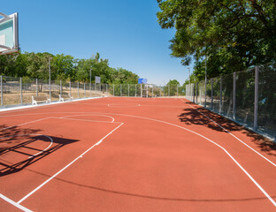 Outdoor basketball court on a sunny day with clear sky and bright sunlight