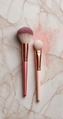 Two makeup brushes, pink hues on veined marble, pink powder