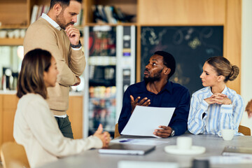 African-American Man Leads Discussion With Asian Woman and Colleagues in a Modern Office Meeting