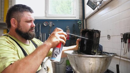 Automotive technician in workshop applying cleaning spray to engine component, showcasing meticulous attention to detail in car maintenance and repair process, emphasizing professional craftsmanship