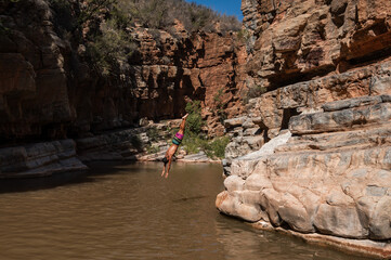 A man jumps headfirst into the water in a ravine. Paradise Valley in Morocco
