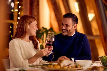Couple Sharing A Glass Of Red Wine At A Cozy Indoor Dinner Date Evening