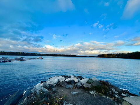 Expansive blue sky with wispy clouds over a calm wide body of water at dusk