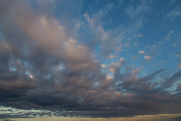 Approaching dark cloud at sunset against the evening sky background.