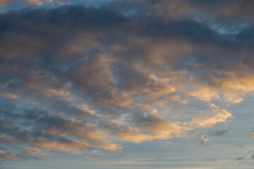 Blurred dark clouds with sunset reflections drifting across the sky dome against the evening sky background.