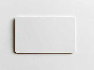 Blank white plastic card against white surface, rounded edges, minimalist, clean, bright, simple object