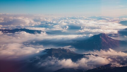 Obraz premium Revealing mountain peaks and ridges rising through cloud blanket from high-altitude, with pale sky