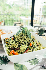 A vibrant image of pesto pasta garnished with fresh basil leaves, ready to be enjoyed. The pasta is...