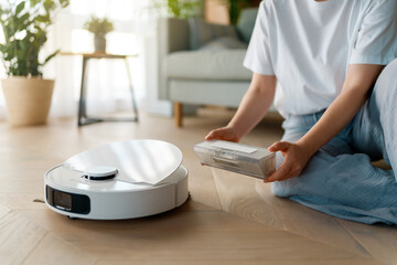 Fototapeta premium White robotic vacuum cleaner on wooden floor