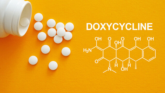 Doxycycline white medical pills spilling out of a drug bottle. Chemical structure of Doxycycline