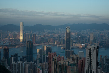 Fototapeta premium Present-day urban skyscraper jungle. Panoramic view of spectacular Hong Kong skyline and Victoria harbor on misty twilight evening