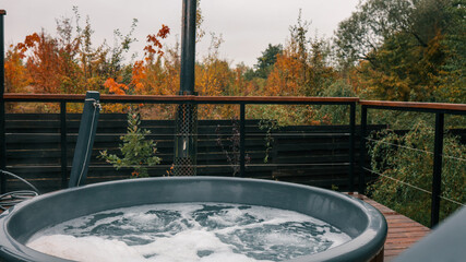 Outdoor hot tub with bubbling water and autumn foliage in the background
