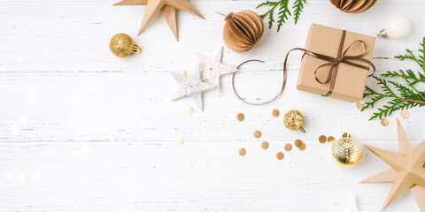 Festive Christmas background with gift box and Christmas decorations on white wooden table. Top view. Copy space for text.