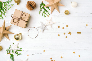 Festive Christmas background with gift box and Christmas decorations on white wooden table. Top view. Copy space for text.