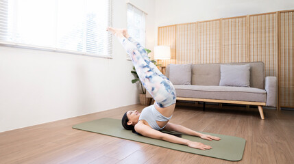 Young woman performing Salamba Sarvangasana (Shoulder Stand) or Viparita Karani (Legs-Up-the-Wall...